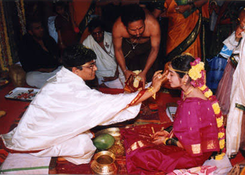 applying kumkuma on woman's forehead in marriage